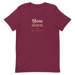 Maroon unisex t-shirt printed "Slow down" with The Sip Collective microphone logo